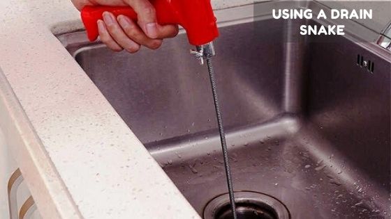 Unclogging the sink using drain snake