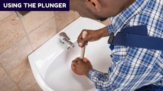 Unclogging a sink clogged with coffee grounds with a plunger